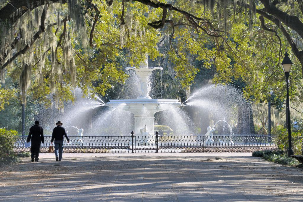 Beautiful fountain and trees as people walk through Forsythe Park in Savannah Georgia. 