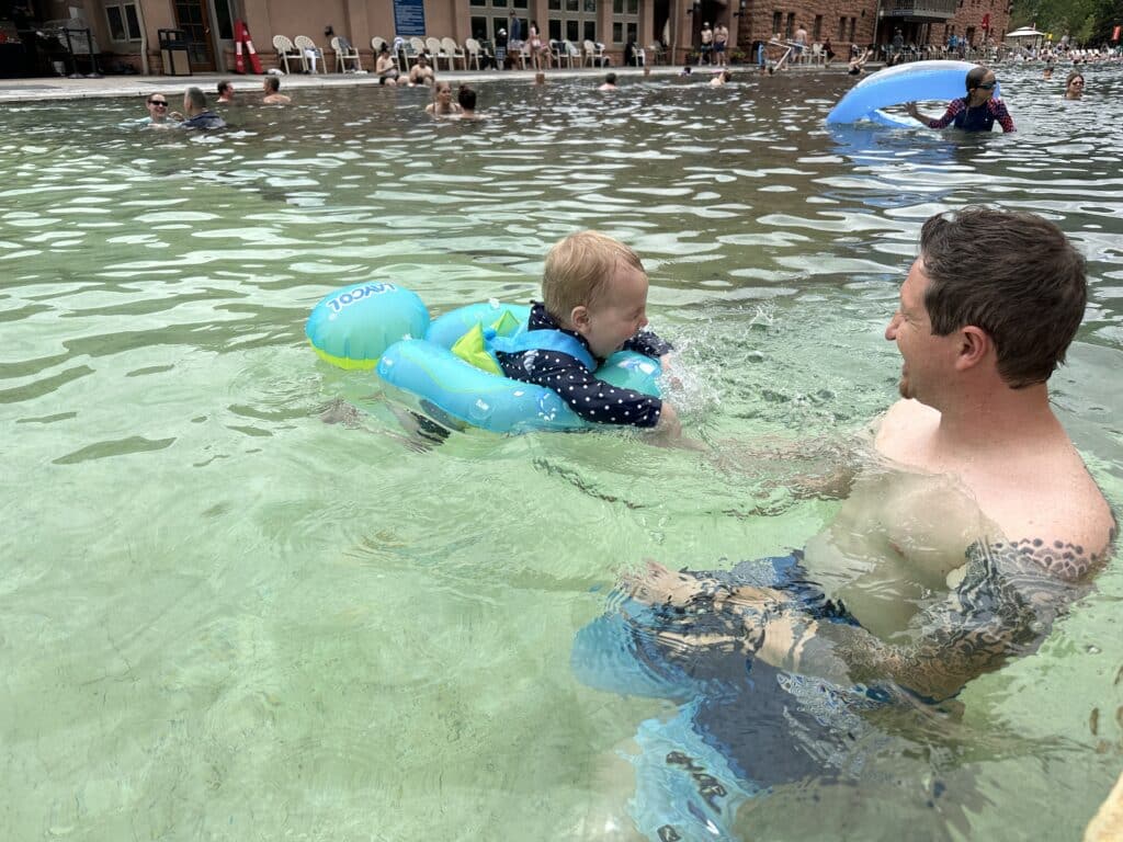 A dad and baby swimming at glenwood hot springs in winter.