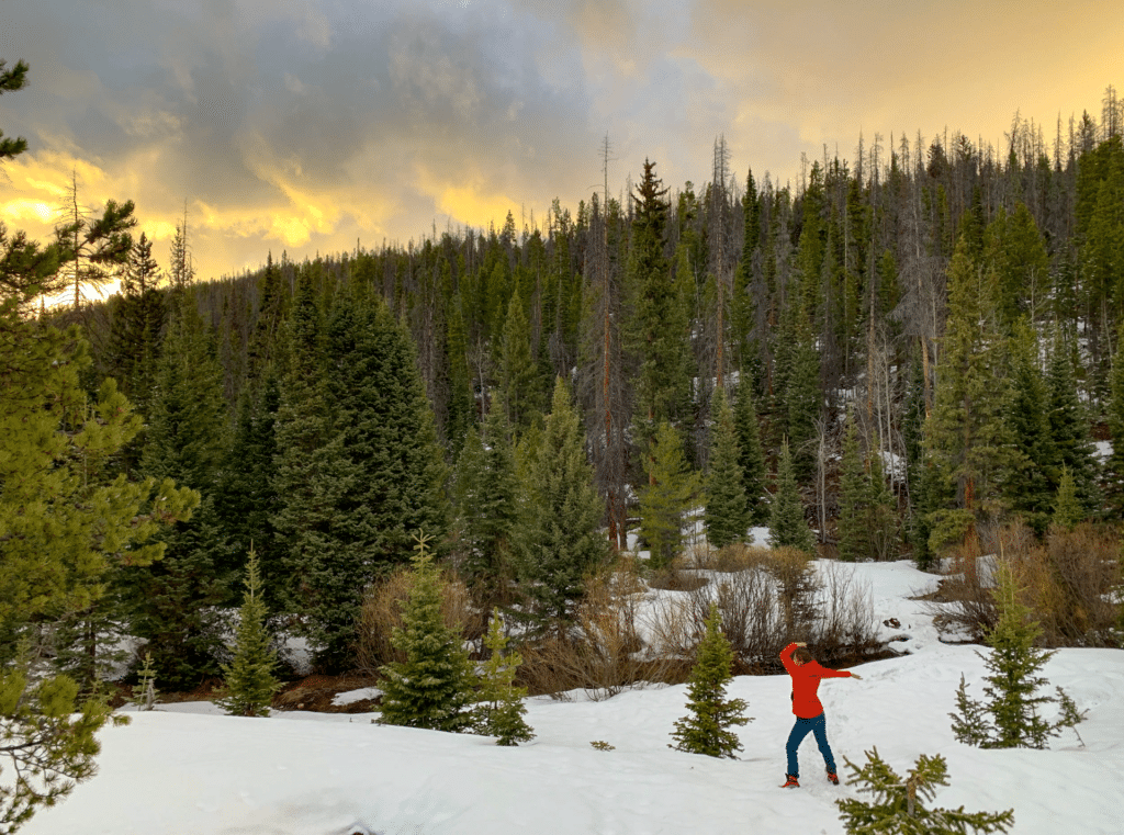 A woman hiking in the snow at sunset in state forest state park