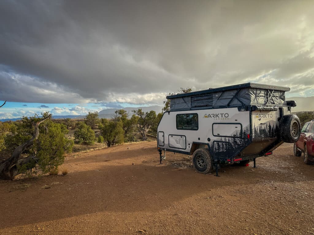 An overland camper parked at a desert camp site on a rainy day.