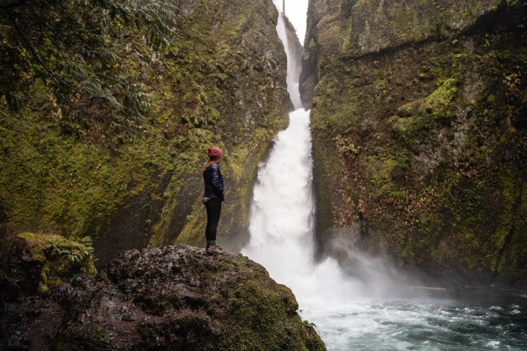 Hiker standing in front of Columbia River Gorge and a waterfall in Washington state. 