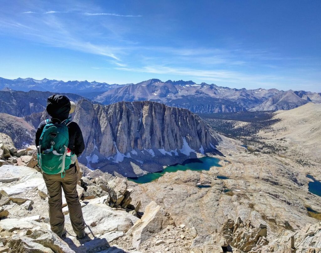 Hiker standing on the summit and admiring the view from the top of Mount Whitney in Sequoia National Park, California. 