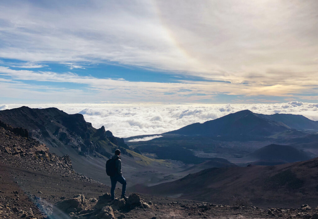 Hiker standing at the summit of Haleakalā Sliding Sands Trail.