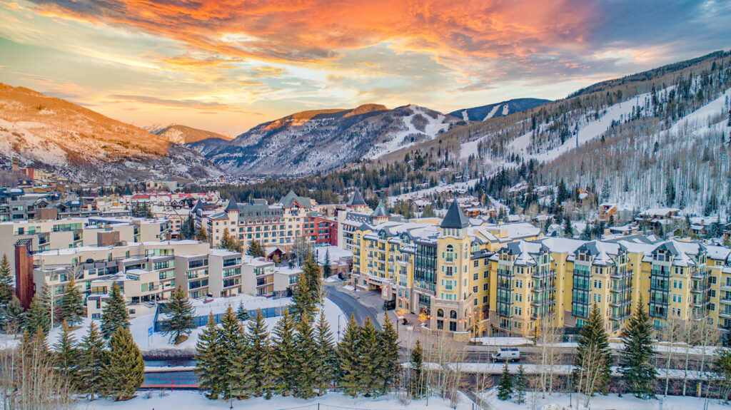 Downtown Vail in winter covered in snow with the sunset in the background.