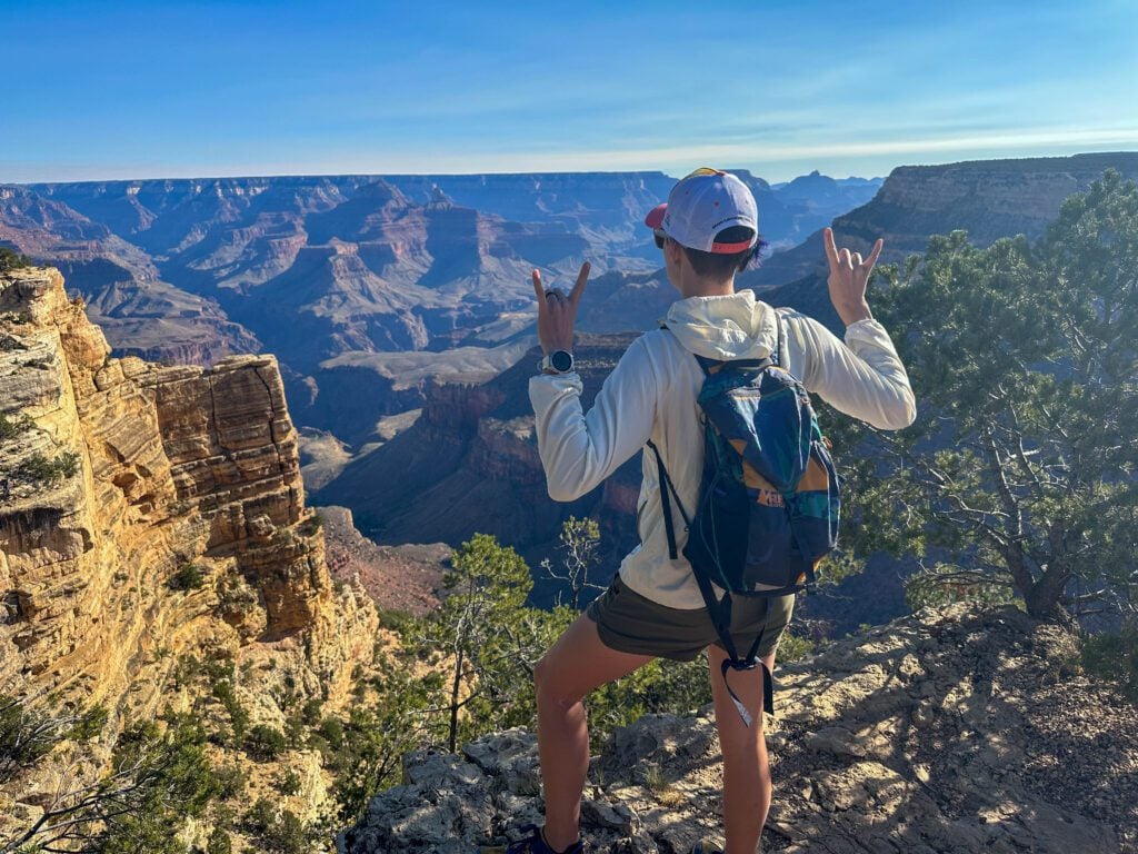 Hermit Scenic Drive in the Grand Canyon with a woman standing in front of an expansive red rock canyon below.