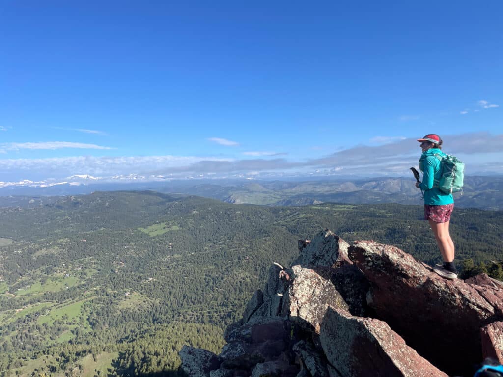 a woman standing on top of a mountain overlooking boulder colorado