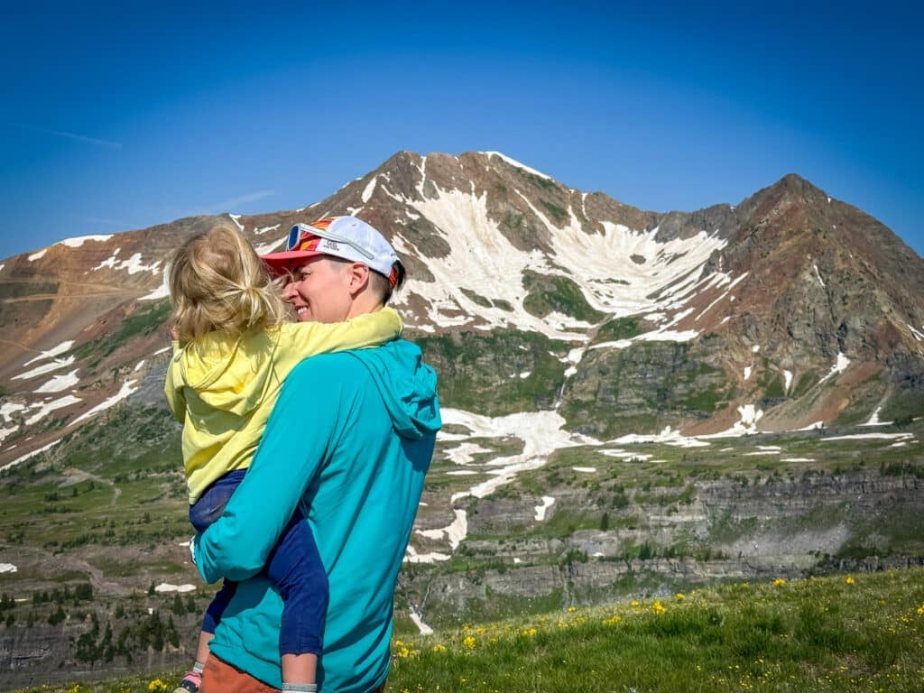a mom and child looking out over snow capped mountains along Scarp Ridge in Crested Butte.