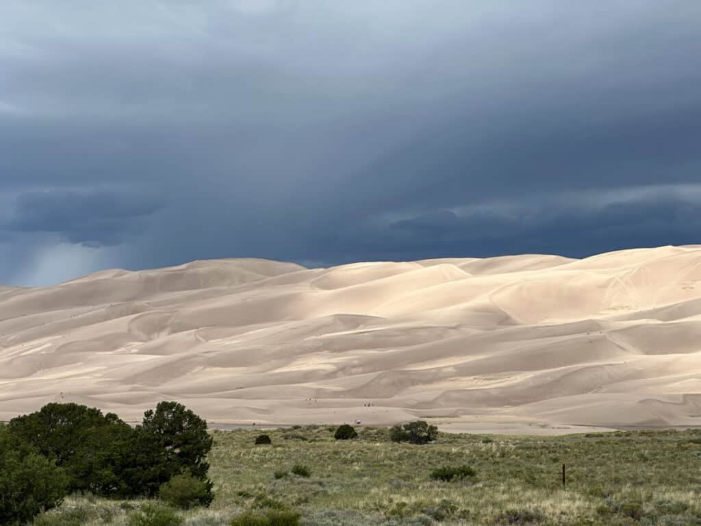 A large sand dune with mountains in the background.