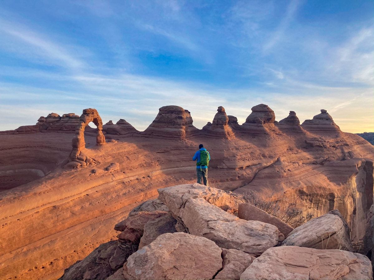 A man standing near Delicate Arch during sunrise in Moab