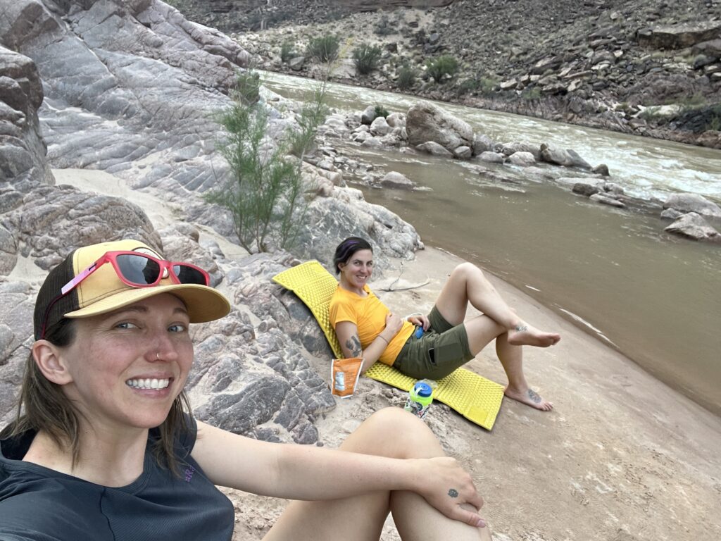 Two women camped on the beach of the Colorado River.