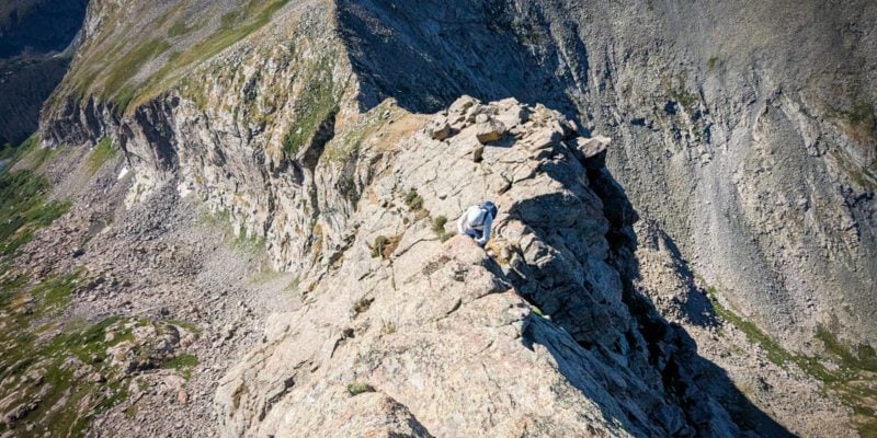 A woman scrambling on music mountain in colorado during the day.