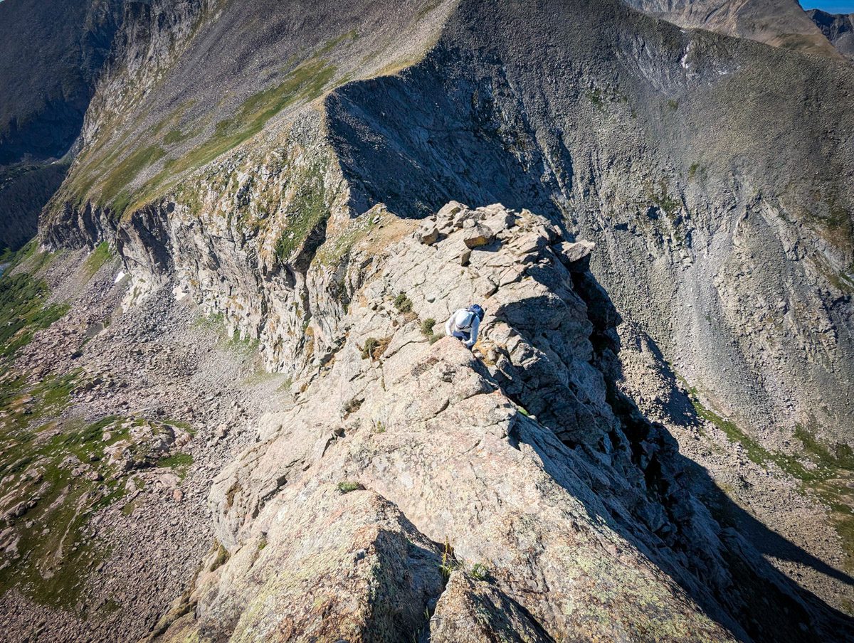 A woman scrambling on music mountain in colorado during the day.
