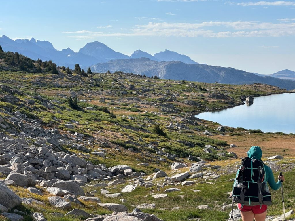 A woman backpacking across a mountain valley.