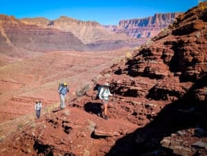 three women on the escalante route in the grand canyon with steep slopes and exposed trails.