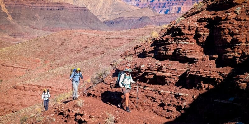 three women on the escalante route in the grand canyon with steep slopes and exposed trails.