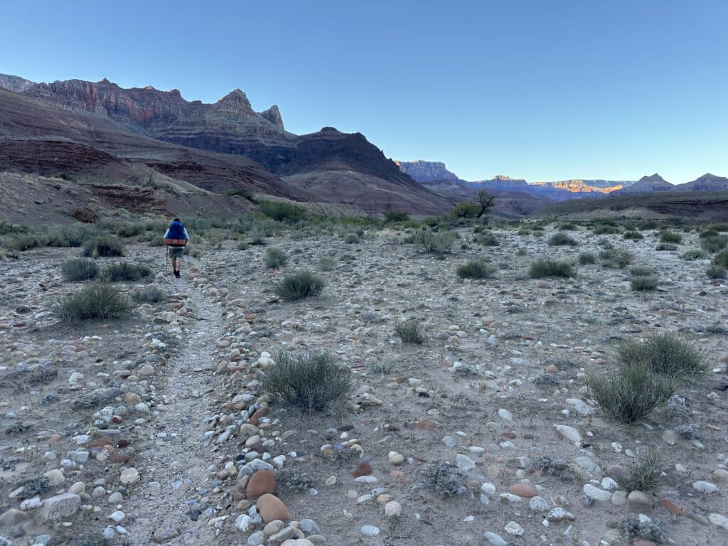 a person hiking through the start of the Escalante Route in the Grand canyon in morning.