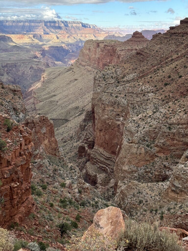 A top down view down a side canyon on a partly cloudy day in the grand canyon.